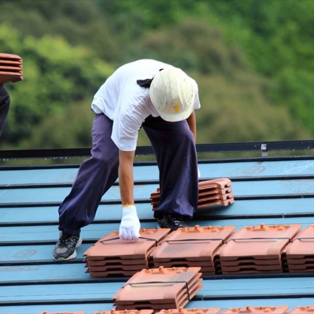 屋根に瓦を並べる職人